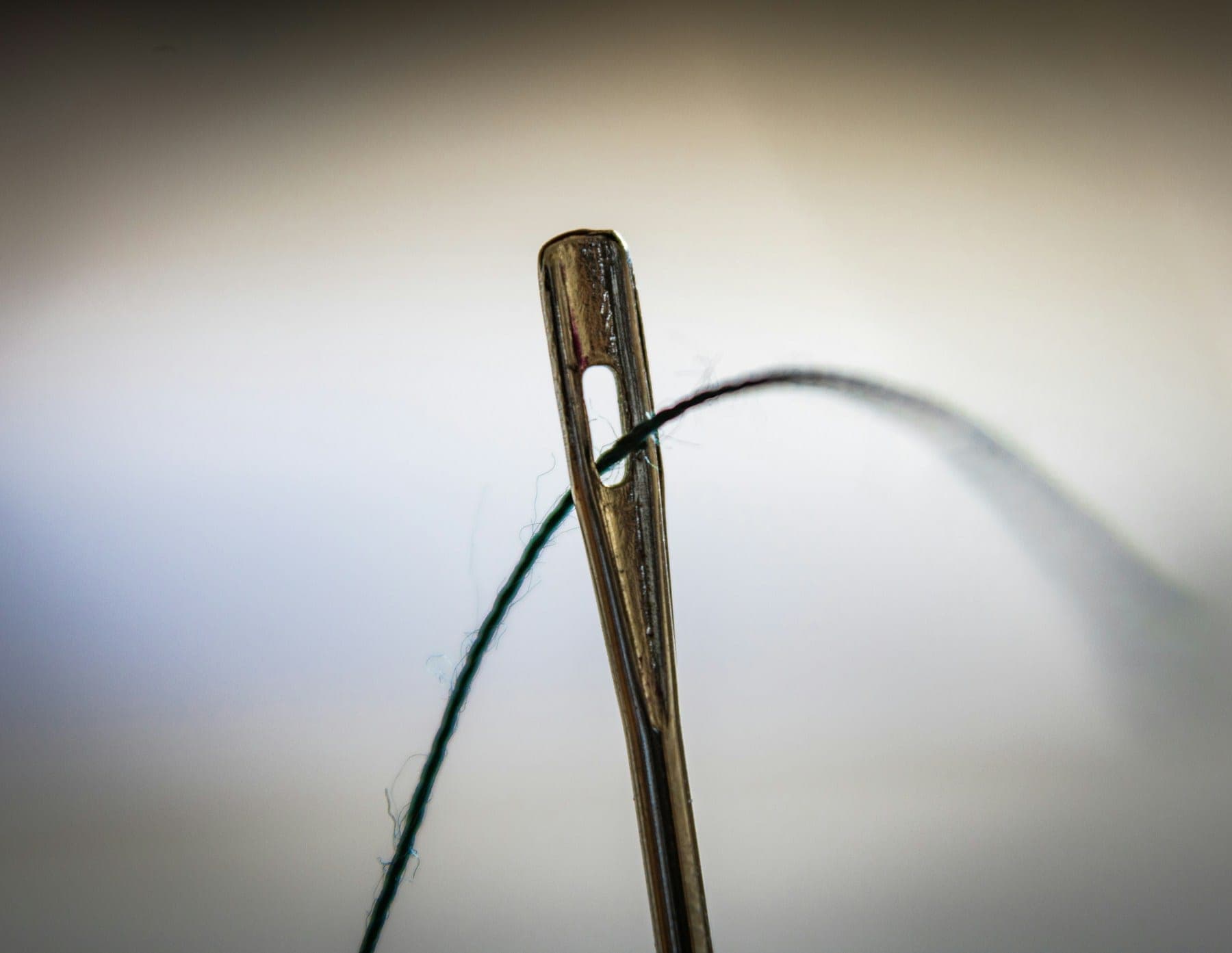 Close-up of a needle eye with dark thread