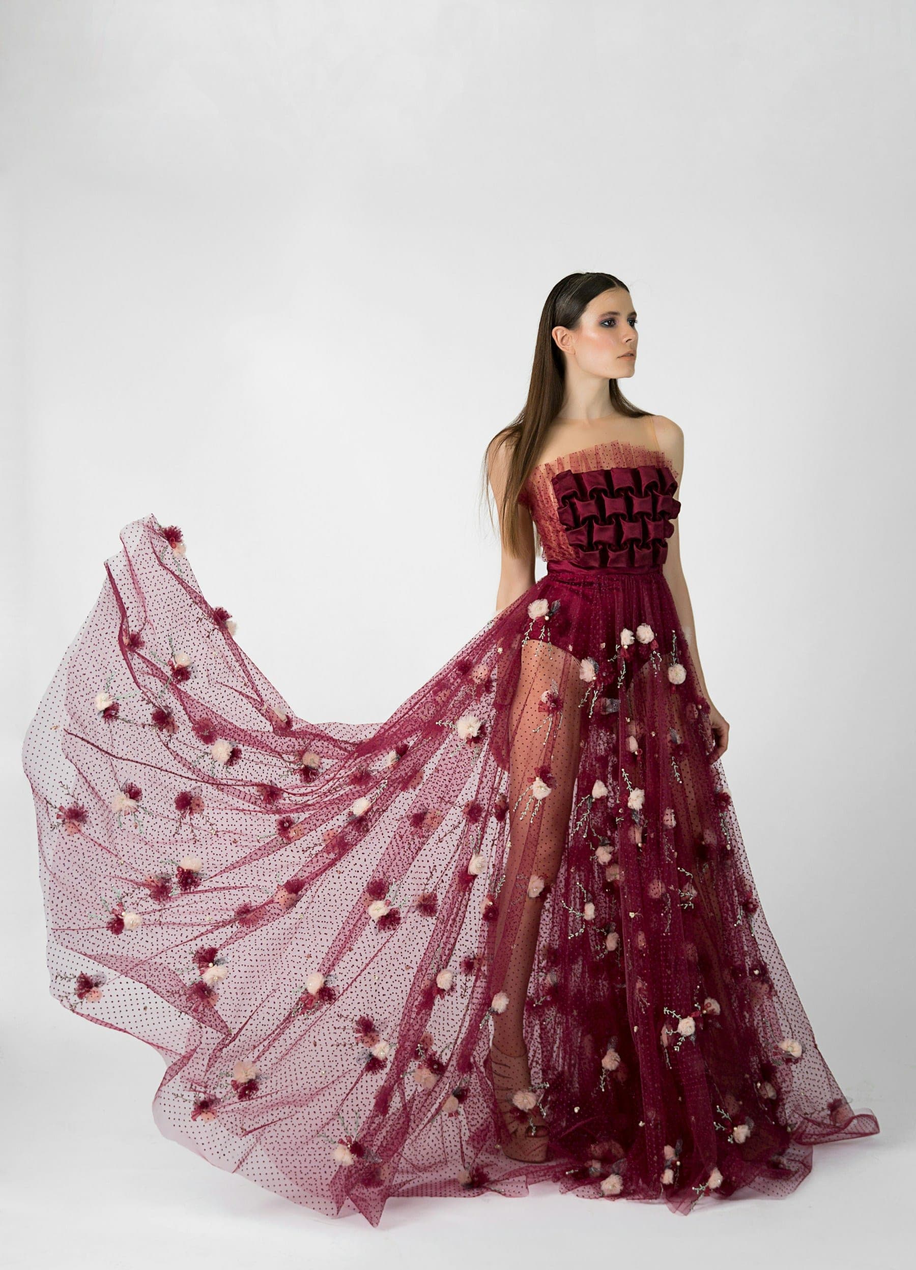 Model in a sheer burgundy gown with floral appliqué