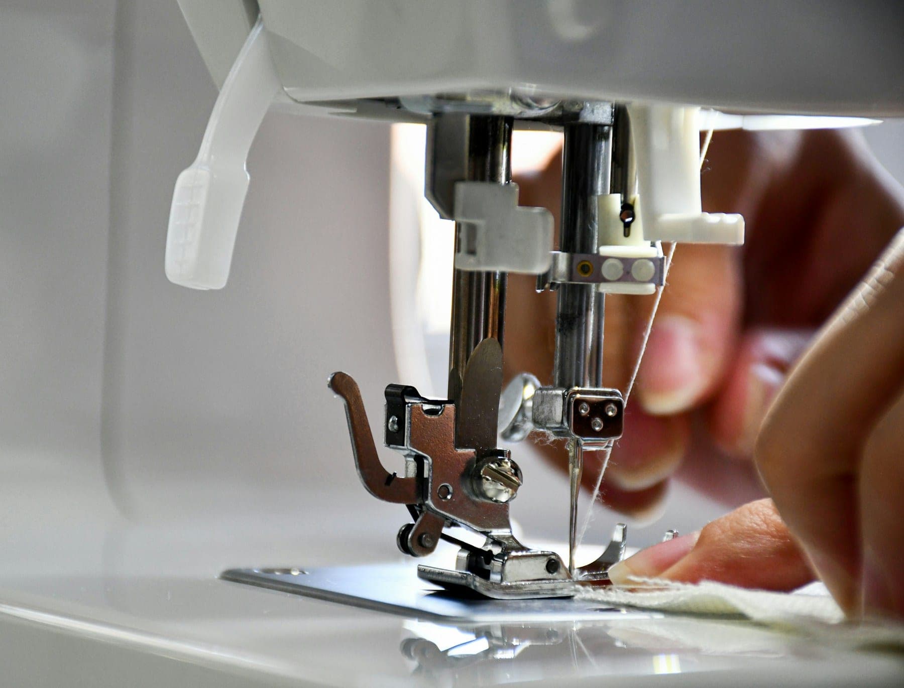 Sewing machine needle stitching white fabric