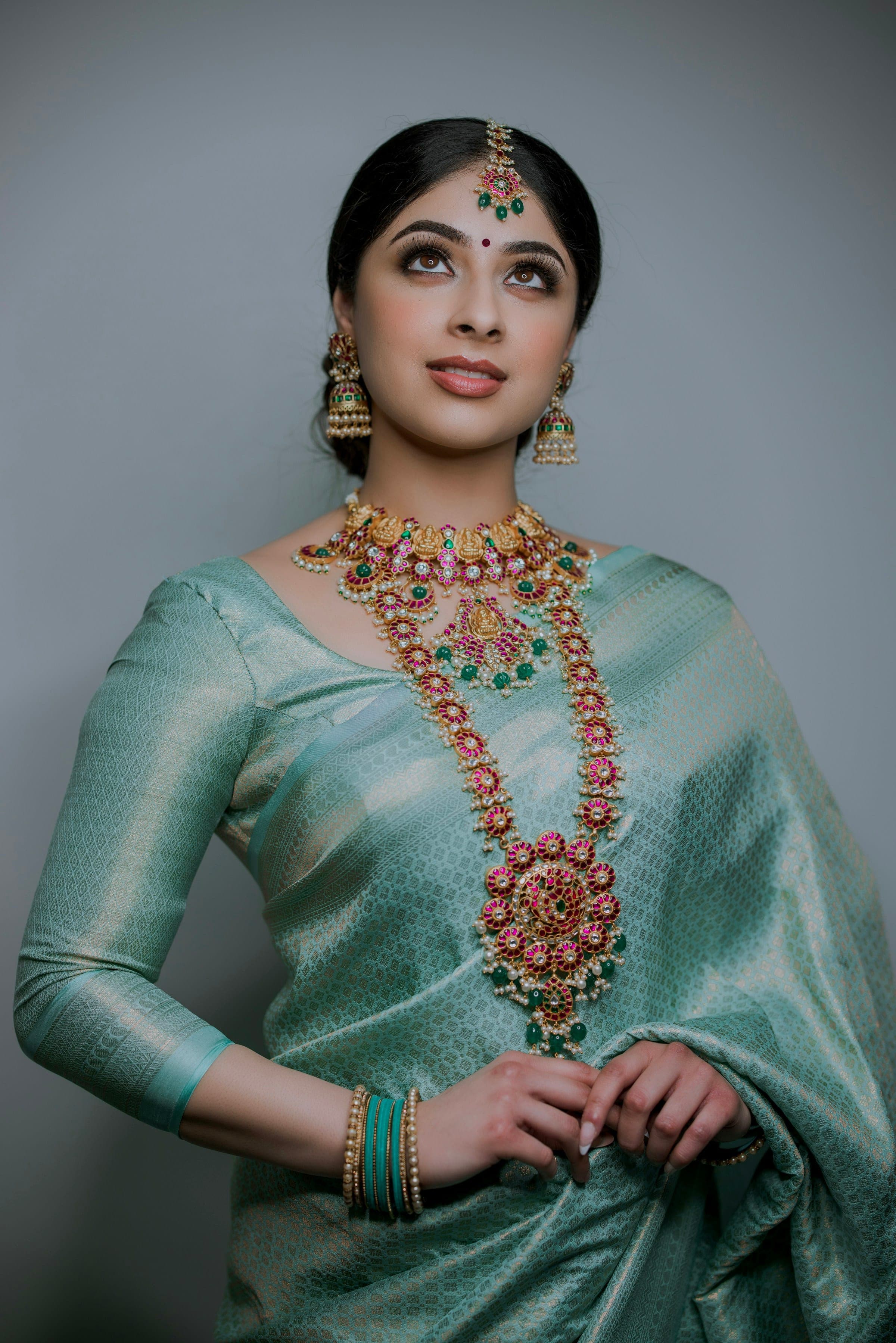 Woman in a sea-green Banarasi silk saree with a statement gold necklace