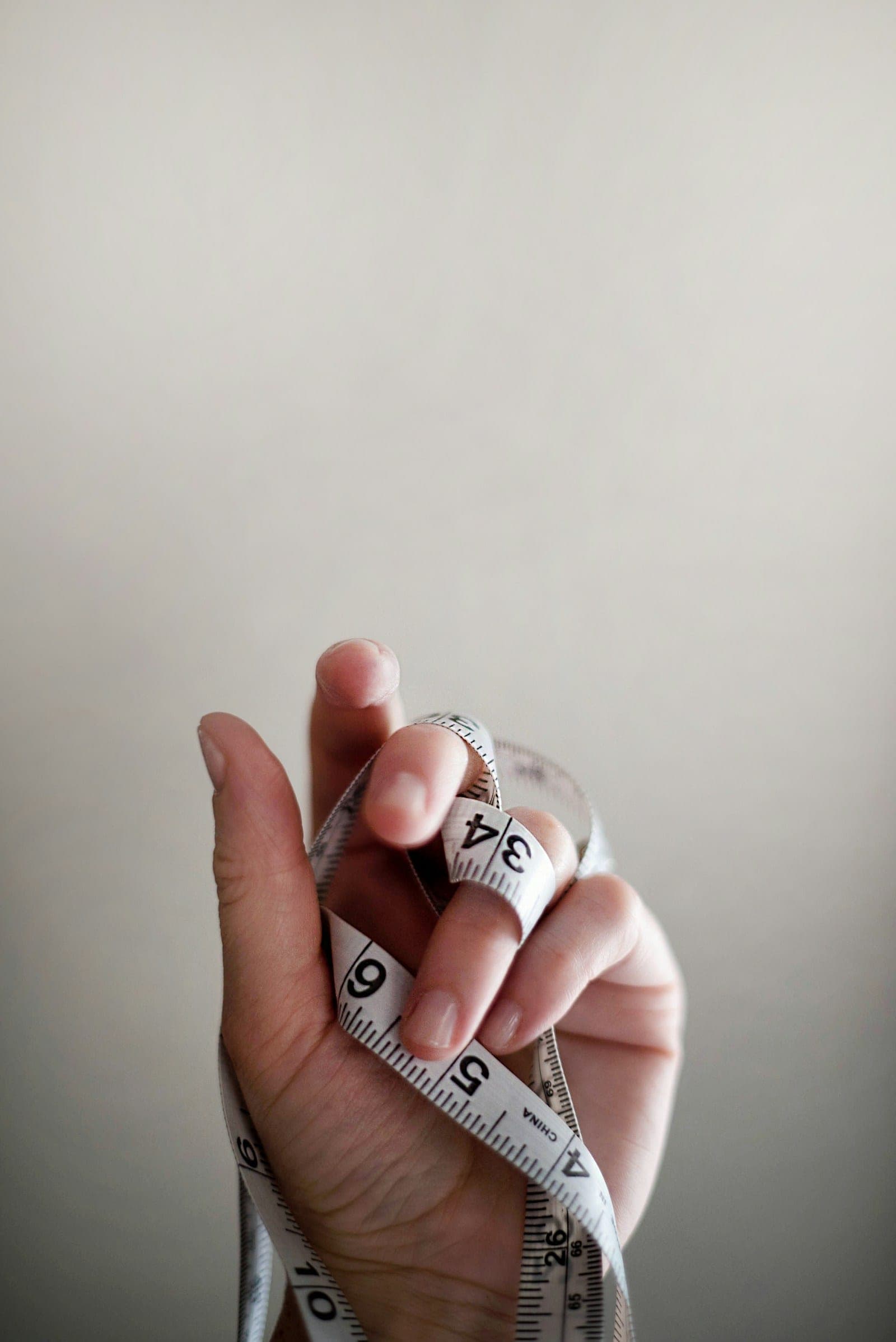 Hand holding a tailor's measuring tape