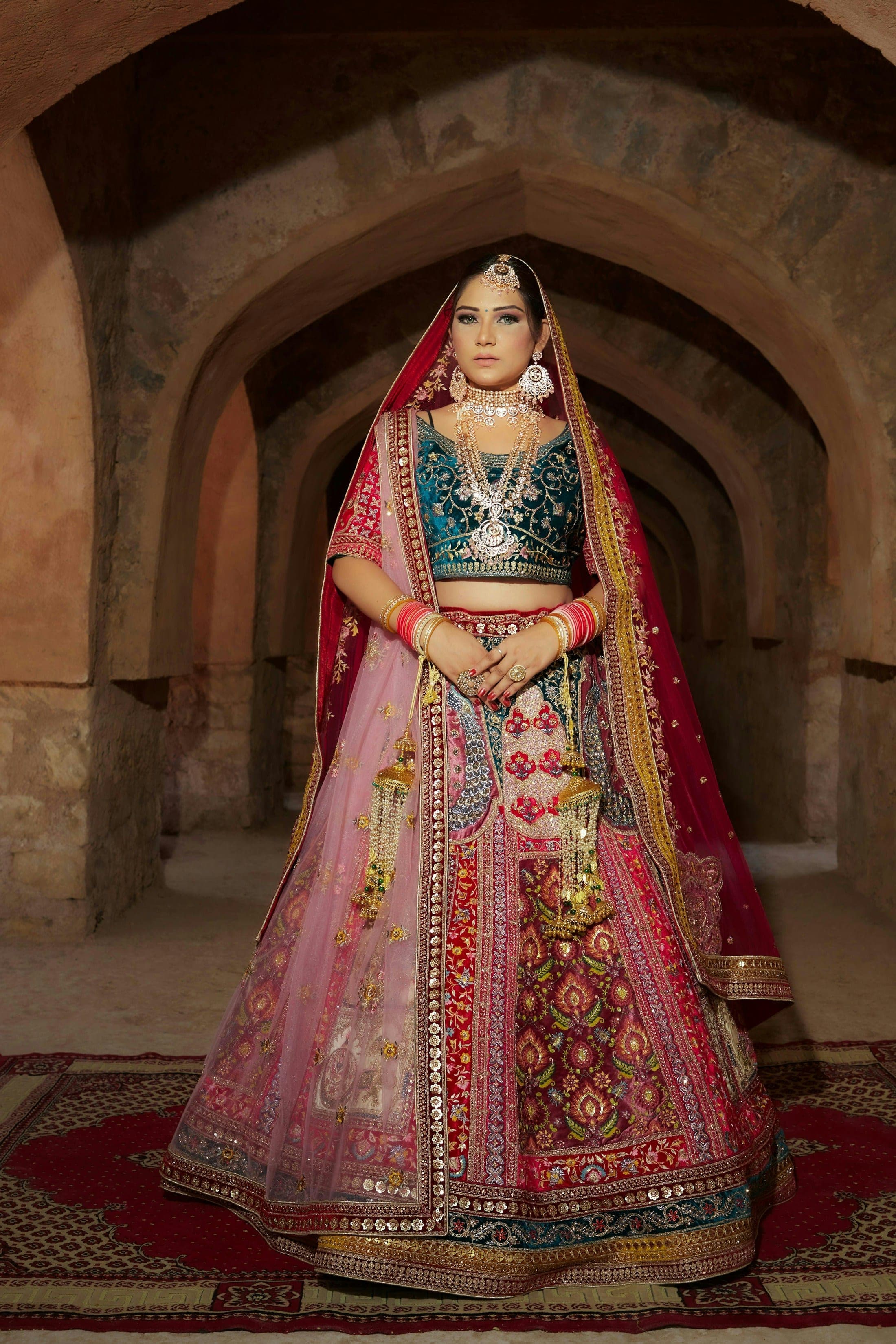 Woman in a richly embroidered lehenga beneath a carved stone archway